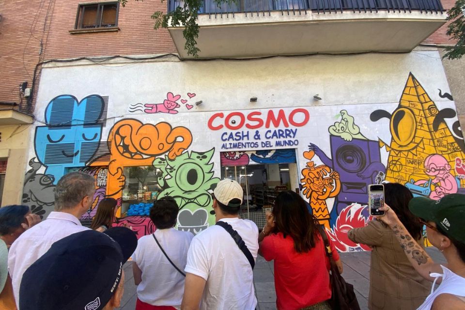 People watching a mural in Lavapiés while listening to the guide explanations