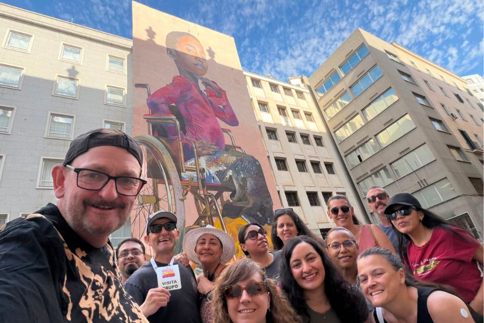 Group of guest posing in front of the mural starting our Malasaña walking tour in Madrid