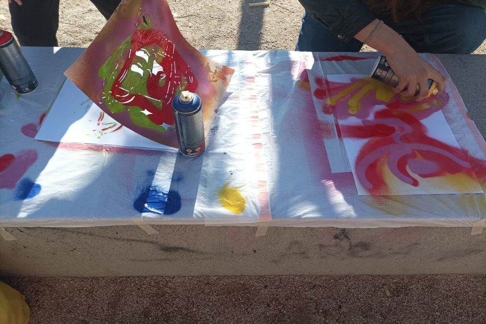 student painting on paper with spray cans and stencils 