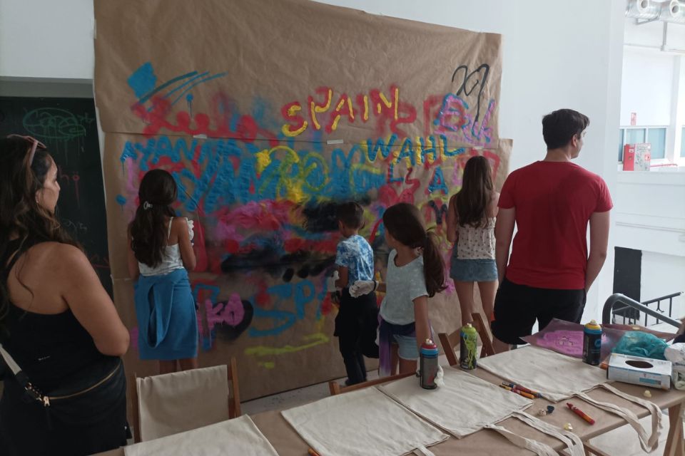 kids painting with spay cans on a wall covered with paper kraft 